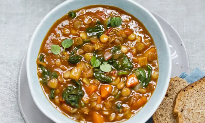 Sopa nutritiva de lentejas acompañada con verduras salteadas, cilantro y limón